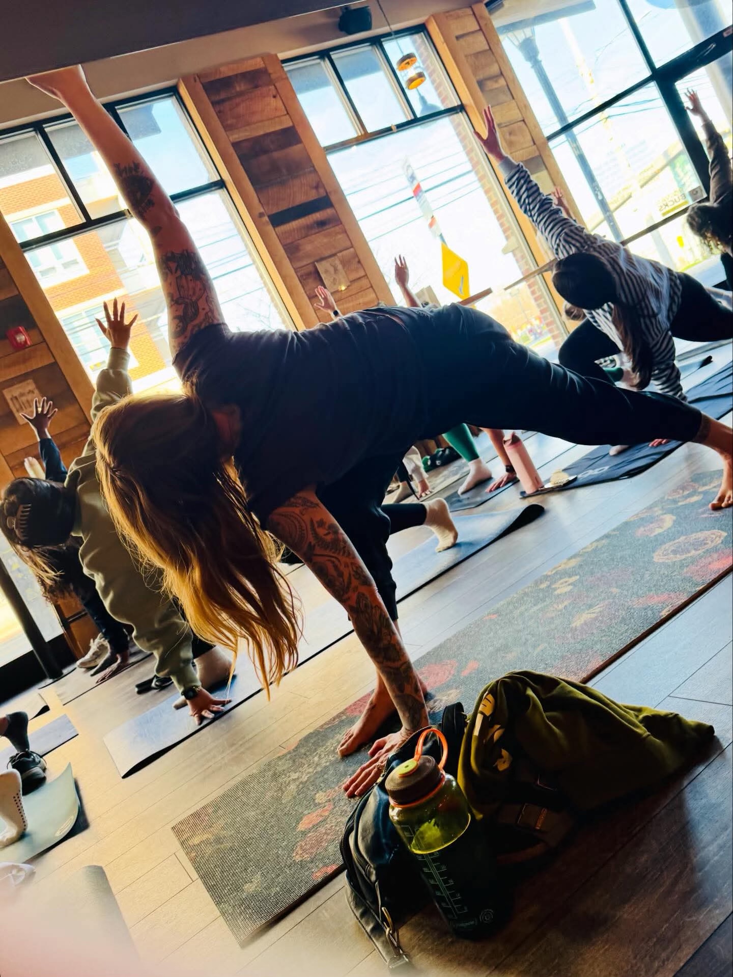 Yoga students in a side-plank pose by the windows at High Grounds Coffee Roasters in Glassboro