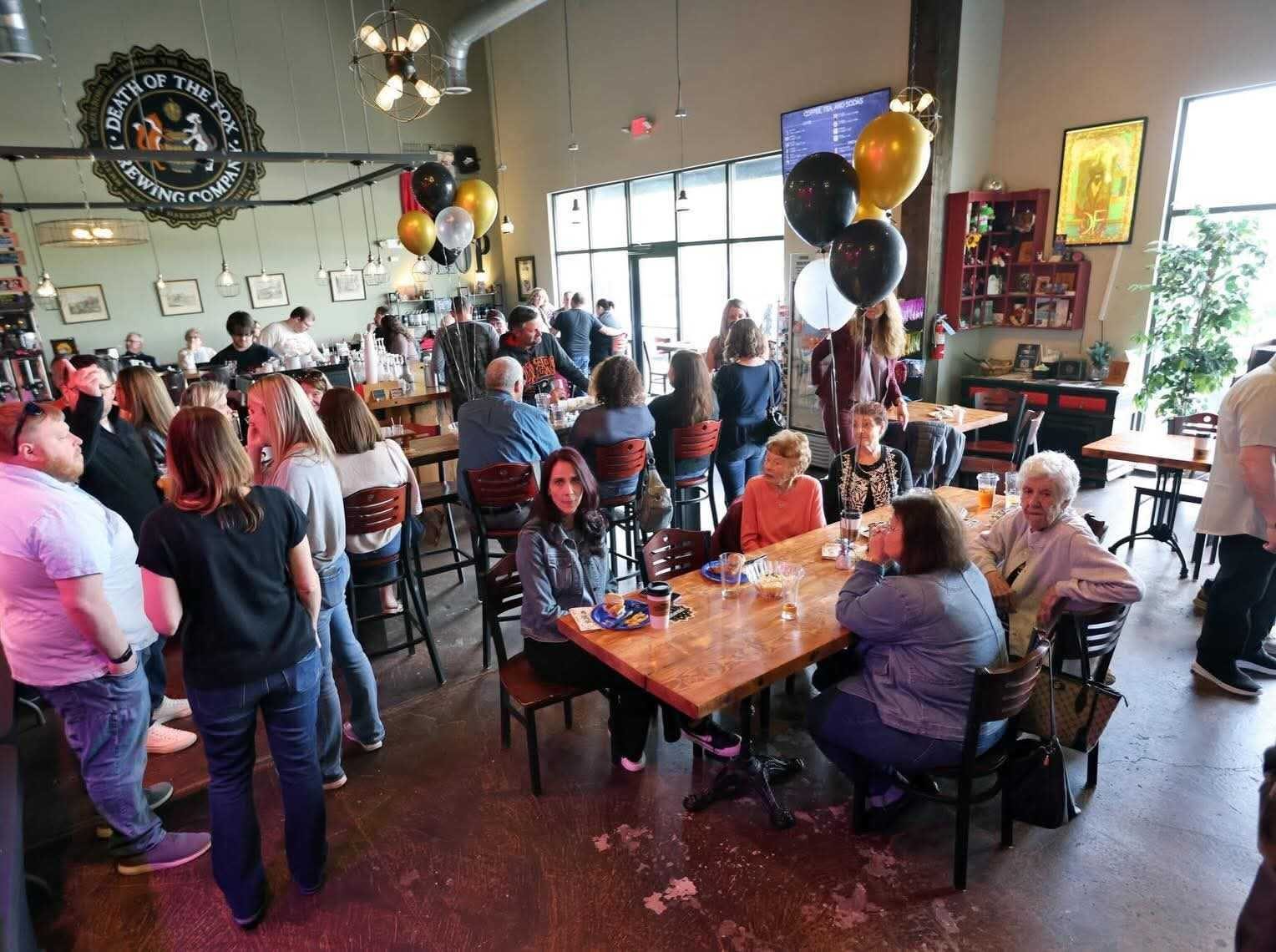 Packed Death of the Fox taproom celebrating with black and gold balloons