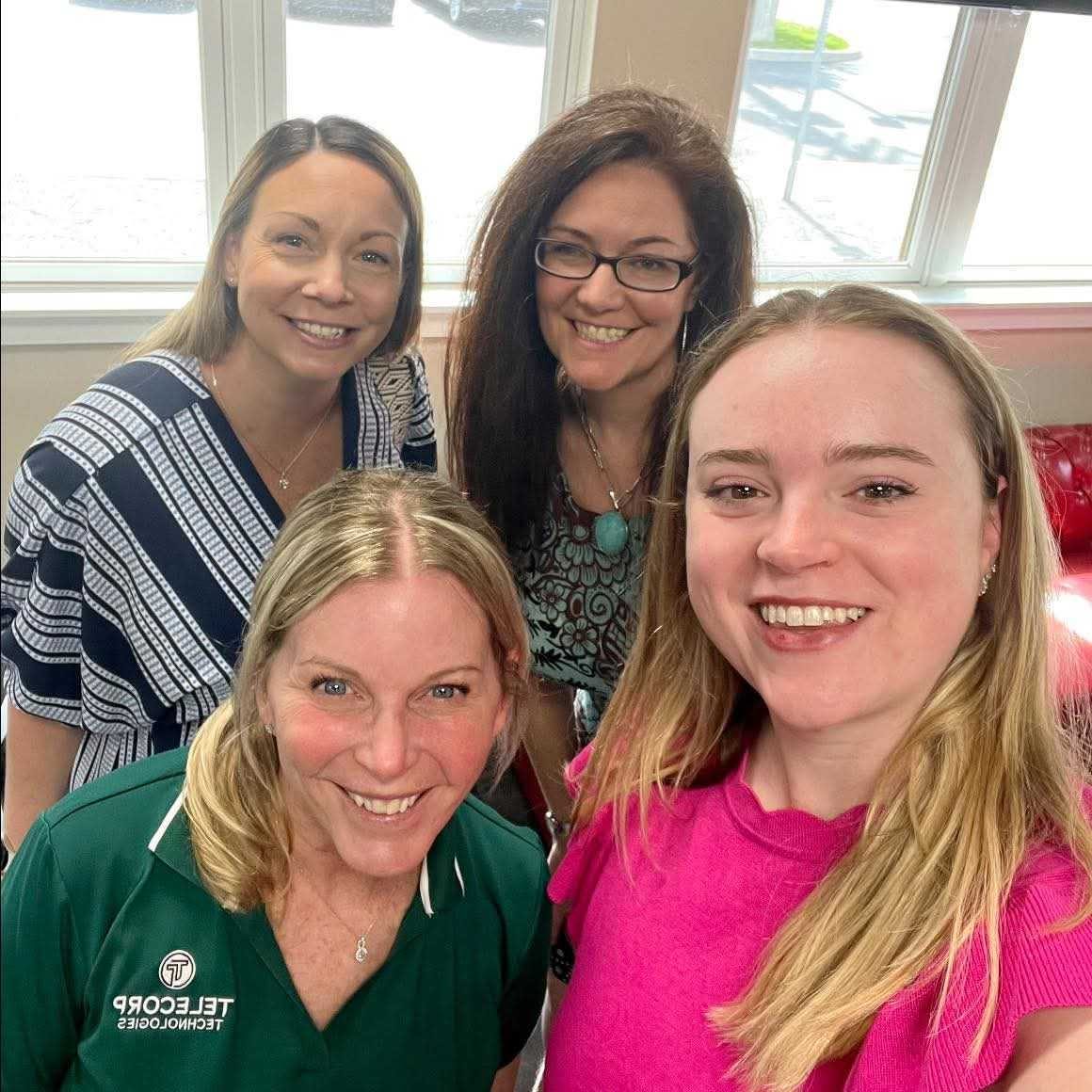 Four women smiling in a selfie at a community business event