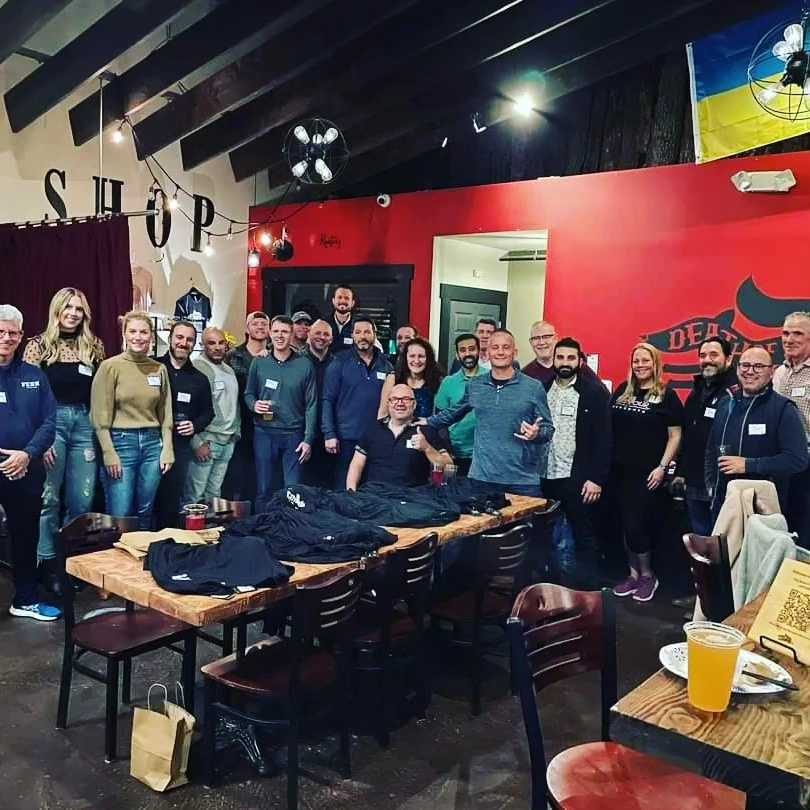 Large business group posing around a long table in the taproom