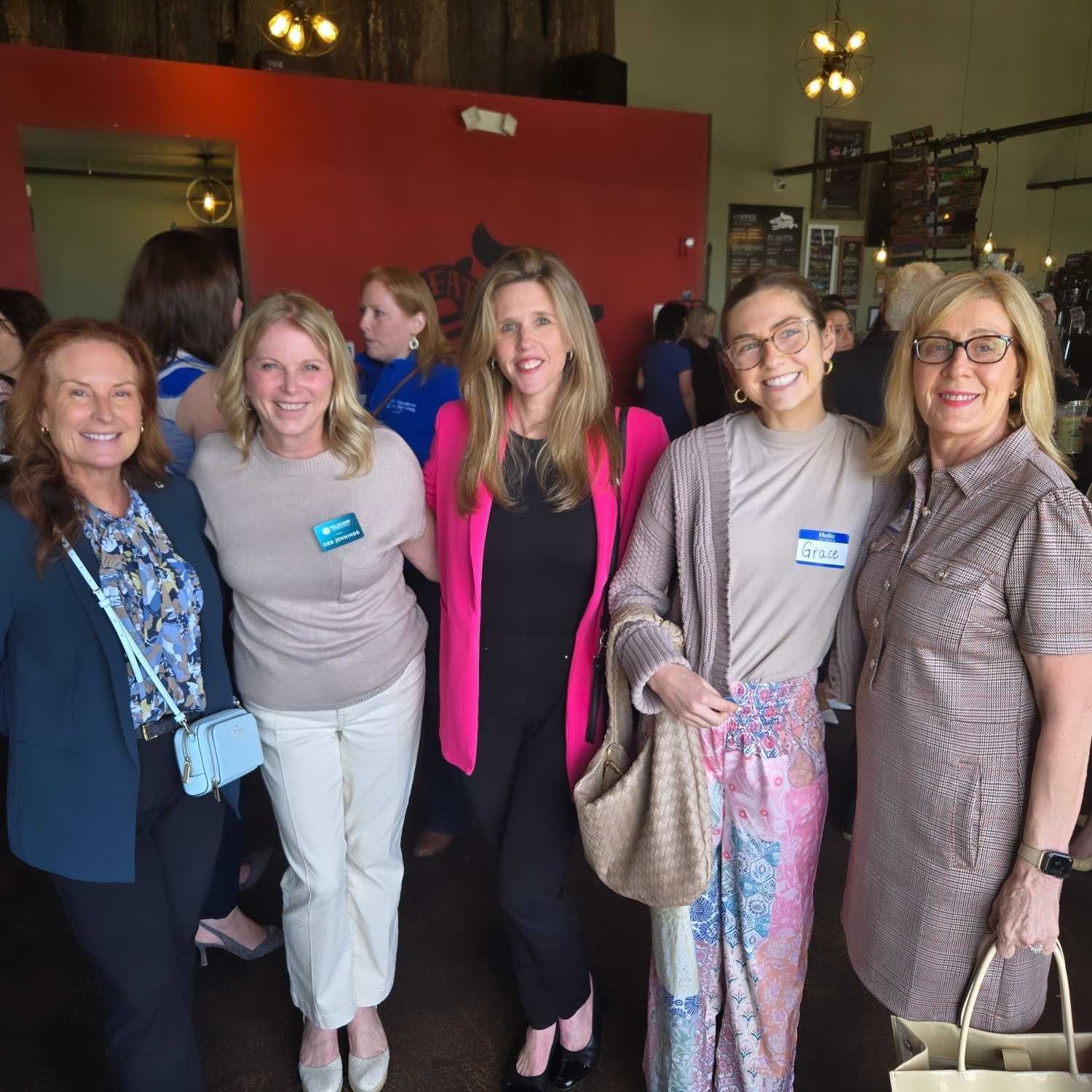 Five women smiling together at a networking event in the taproom
