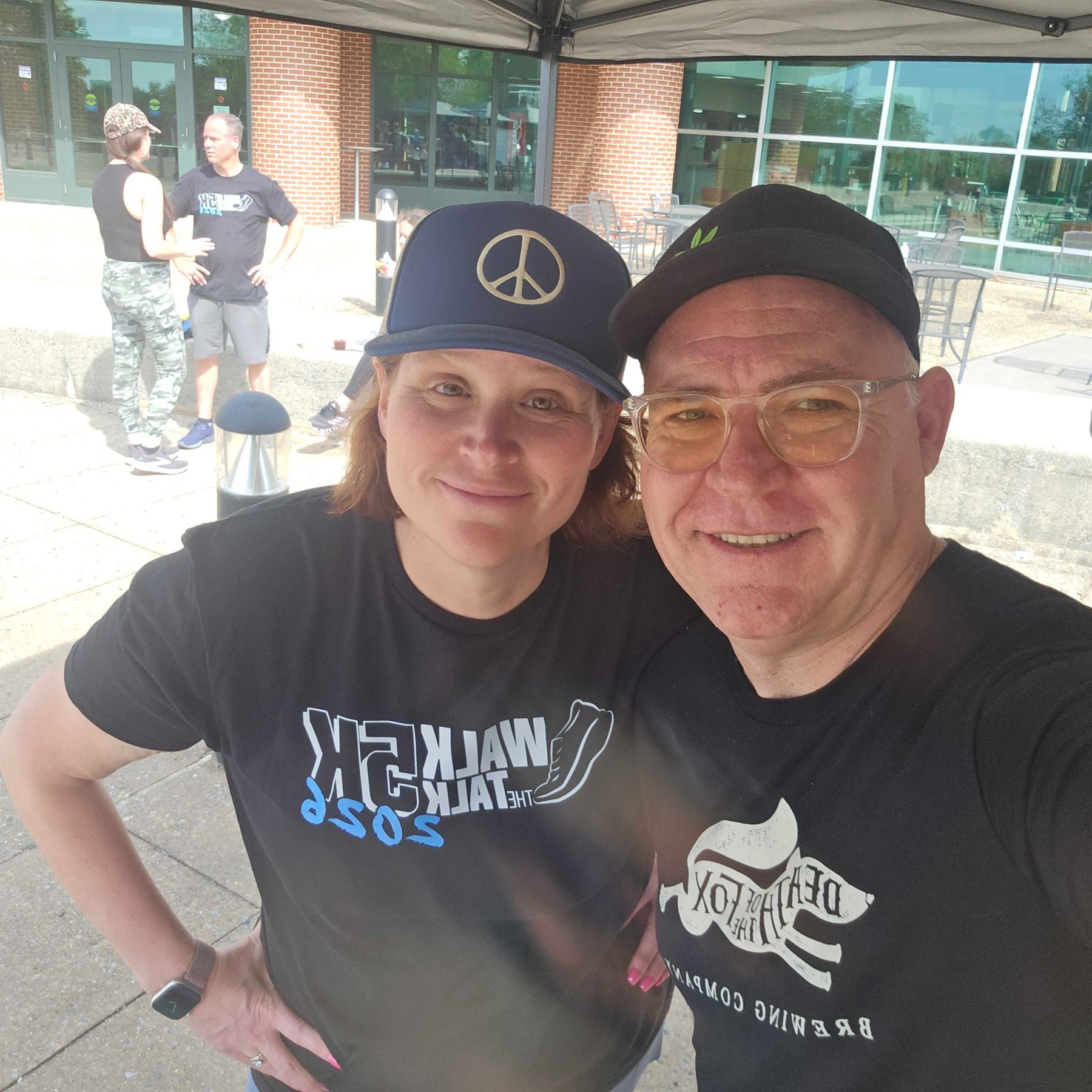Two runners in Walk the Talk 5K 2026 and Death of the Fox shirts at the race tent