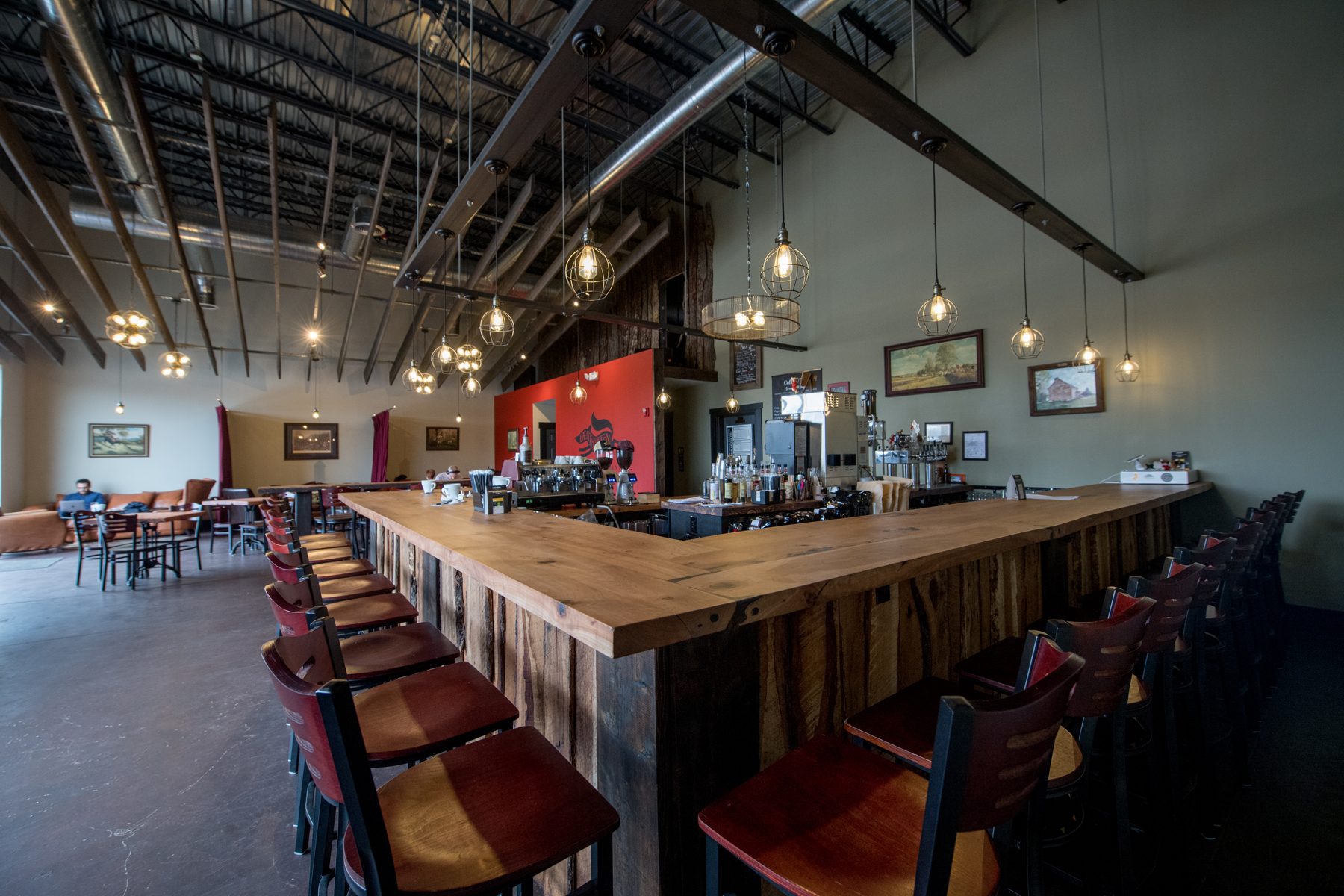 Long wooden bar with red stools in the Death of the Fox tasting room