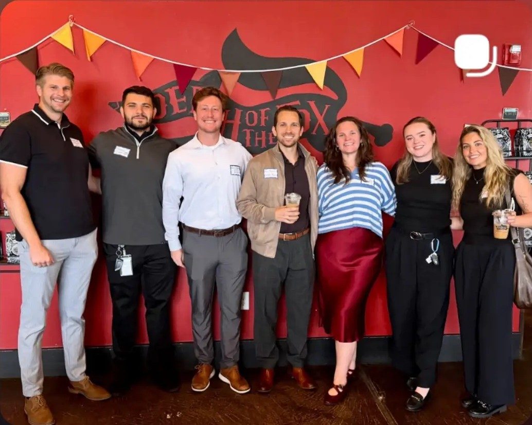 Young professionals networking group posing under the Death of the Fox mural