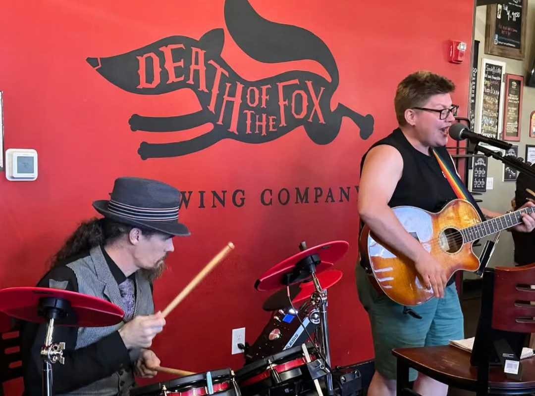Drummer and guitarist performing a duo set beneath the Death of the Fox mural